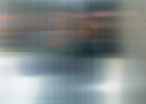 Convex polished shiny steel metal surface with multicolored reflections and glare.