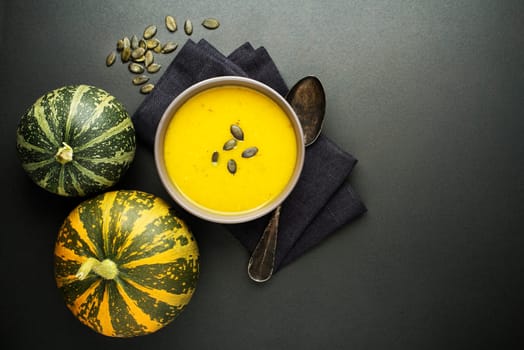 Pumpkin and vegetable soup with cream on dark background Top view