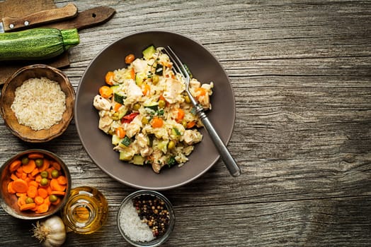 Risotto with chicken and vegetables served on wooden table