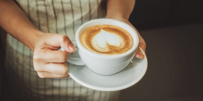 Close-up hand of a waitress serving a cup of coffee to customer. Selective focus.