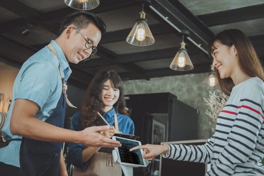 Asian baristas are recommending coffee menu to customer. Cafe restaurant service, food and drink industry concept.