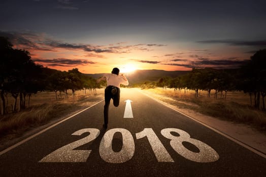Back view of businessman running on the street with 2018 number at sunset background