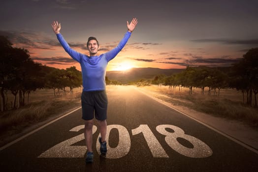 Happy asian man reach the finish with 2018 number on the street at sunset background