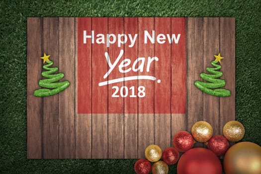 Christmas decoration with message of Happy New Year 2018 on wooden board on the grass