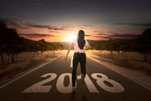 Back view of businesswoman running on the street with 2018 number at sunset background