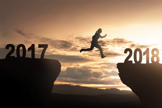 Silhouette of woman jump toward 2018 with sunset background