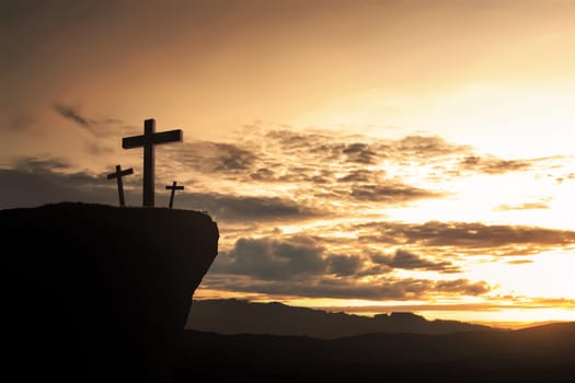 Christian cross on the hill at sunset background