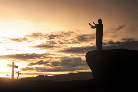 Silhouette of man facing the cross and praying with sunset background