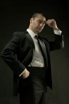 The attractive mature man in black suit on dark studio background