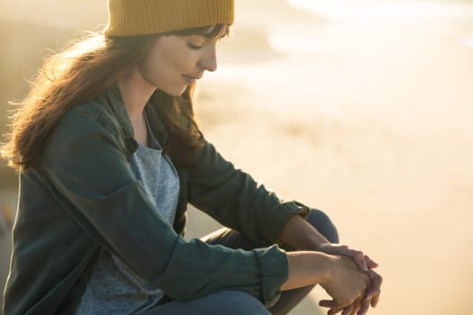 Beautiful woman with yellow cap over the cliff seeing the beach
