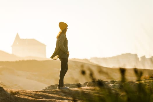 Beautiful woman with yellow cap over the cliff seeing the beach