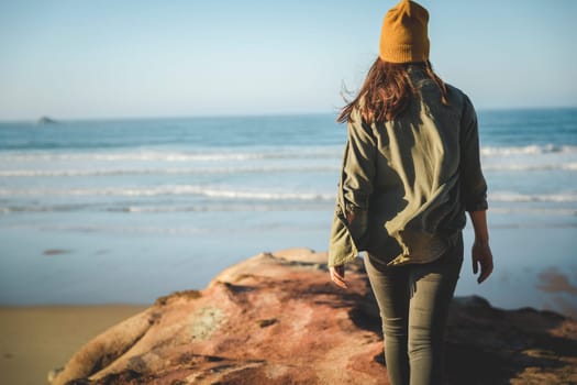Beautiful woman with yellow cap over the cliff seeing the beach