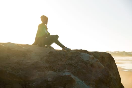 Beautiful woman with yellow cap over the cliff seeing the beach