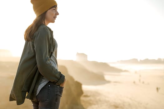 Beautiful woman with yellow cap over the cliff seeing the beach