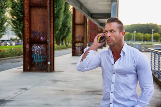 Fit man outdoor in urban environment using cell phone, large copyspace
