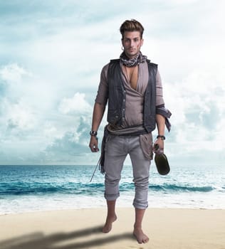 Handsome young pirate on the beach, barefoot, holding wine bottle, looking at camera