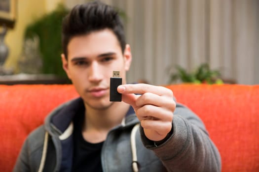 Handsome young man showing USB key in his hand, focus on the electronic drive