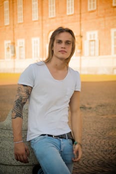 Handsome Long Hair Man on White Shirt Standing in Square in Turin city Center, Italy, with Old Palace Behind Him