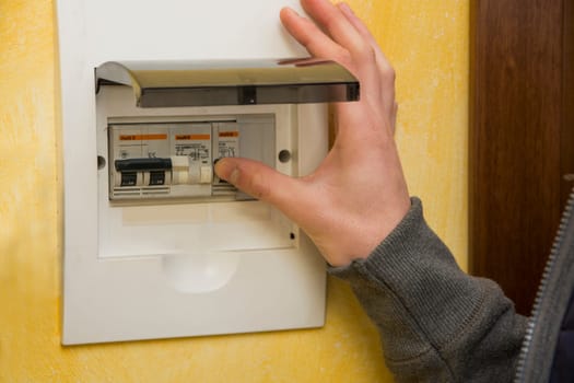 Close up of male hand using an electronic control panel, to switch on electricity at home