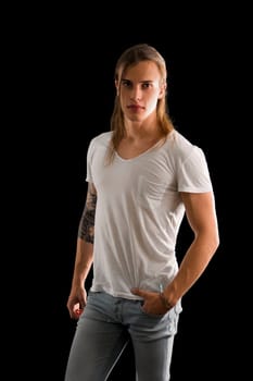 Handsome long hair young man isolated on black, looking intensely at camera with confident expression