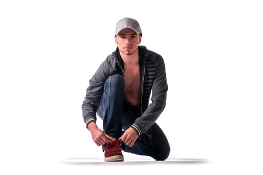 Handsome young man kneeling and tying sneaker show, ready to run. Isolated on white