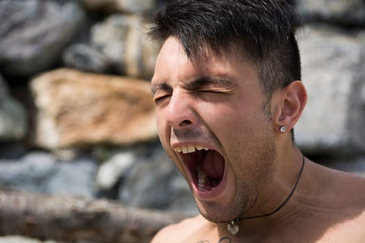 Handsome young man outdoor yawning or screaming
