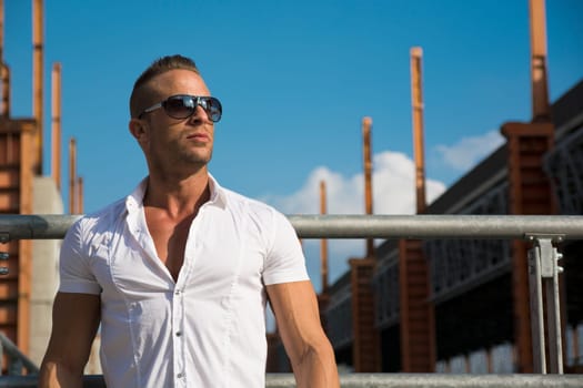 Handsome muscular blond man standing in city setting or former industrial environment