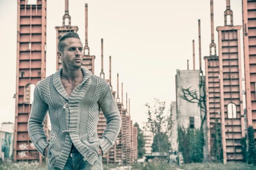 Handsome muscular blond man standing in city setting or former industrial environment
