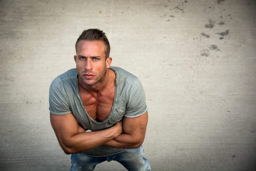 Handsome blond muscular man shot from above, looking at camera, standing outdoor