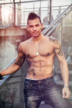 Handsome fit athletic shirtless young man in city setting on metal stairc steps