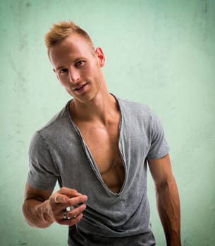 Fit male model with a lot of confidence smiling and pointing finger to camera on green background