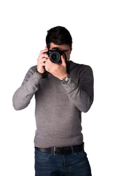 Handsome young man taking photo with professional photocamera, standing isolated on white