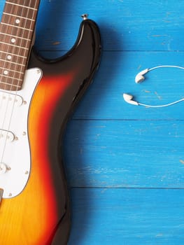Music concept image, vintage guitar with earphones on a rustic wooden background, Jazz, rock or blues music concept
