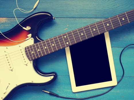 Music concept image, vintage guitar with earphones on a rustic wooden background, Jazz, rock or blues music concept