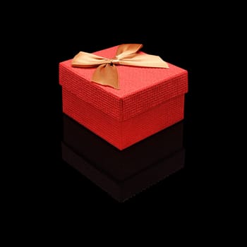 Gift box close paper texture red with a bow on a black glossy background with real reflection. Isolated.