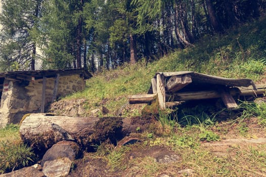 Old wooden fountain in the mountain and forest in background. Photo in vintage style.
