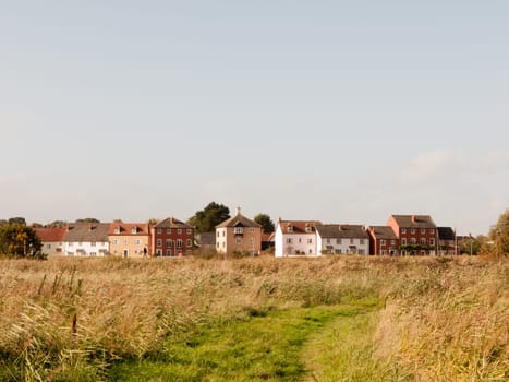meadow in front of a row of house in front of blue sky  essex  england  uk