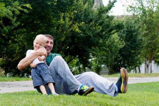 Laughing happy father and son are playing outdoors.