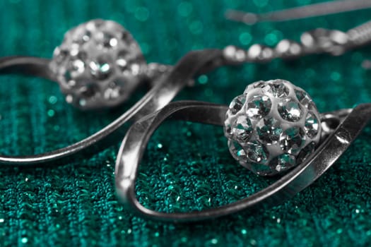 Macro photo about luxury silver earrings on turquoise background.