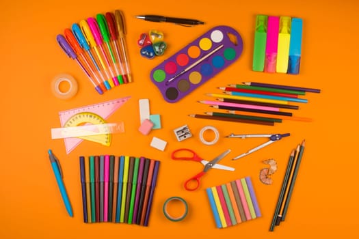Different school supplies are on orange background.