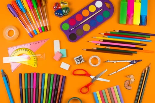 Different school supplies are on orange background.
