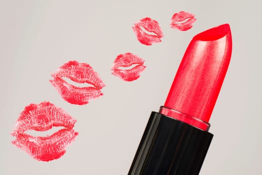 Red lipstick and red lipstick kisses are on gray background.