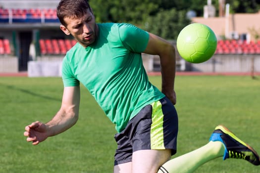 The football player is playing football on the sport field.