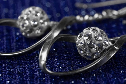 Macro photo about luxury silver earrings on dark blue background.