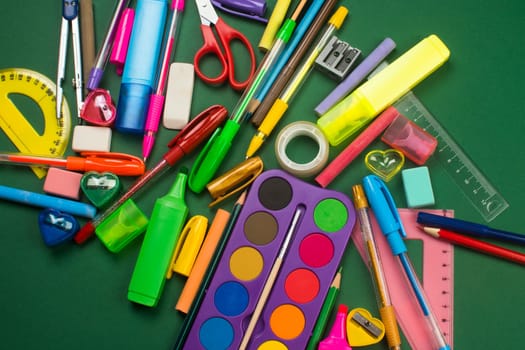 Different school supplies are on green background.