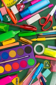 Different school supplies are on green background.