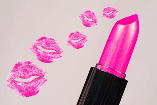 Pink lipstick and pink lipstick kisses are on gray background.