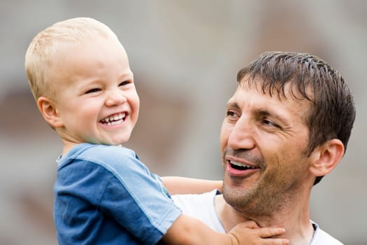 Happy laughing family, uncle and boy on gray background.
