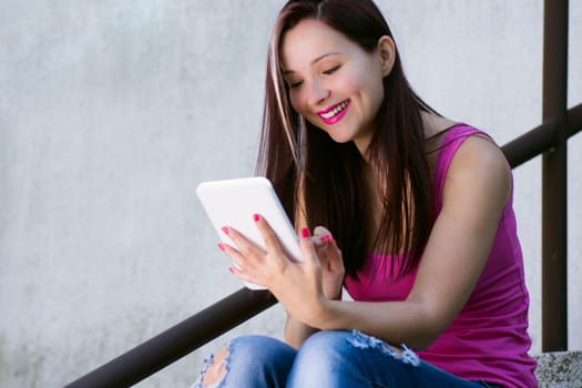 Beautiful smiling young woman with white tablet outdoors.