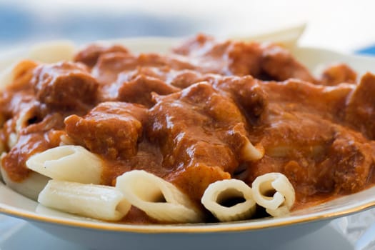 Beef stew, goulash with pasta is in plate.